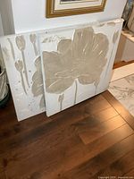 Pair of square textured floral canvases leaning against wall