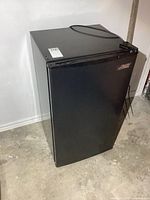Full view of closed black Arctic King bar fridge with power cord