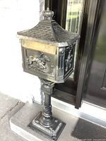 Front view of cast iron pedestal mailbox against doorway