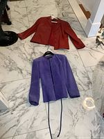 Purple and red Danier leather jackets laid on marble floor