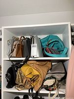 Shelf showing multiple handbags: teal, brown, silver, yellow, black, sequined gold, beige, white floral, etc.