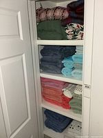 Full closet view showing throws on top shelf and assorted towels on three lower shelves