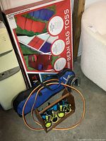 Bean bag toss box, wooden crate with lawn darts, horseshoe visible