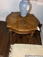 Top view of round scalloped wooden side table with veneer pattern