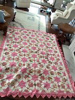 Overall view of pink and white patchwork quilt laid out on floor