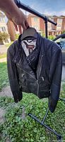 Front view of black Danier leather moto jacket on hanger