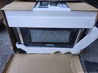 Oven front visible inside open cardboard box with protective foam