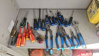 Group of screwdrivers, pliers and adjustable wrench on shelf
