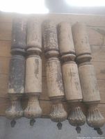 Eight antique wooden table legs laid side by side showing full length, finish wear, fluted feet, casters attached