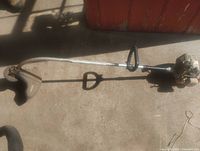 Full view of gas string trimmer showing shaft and cutting head