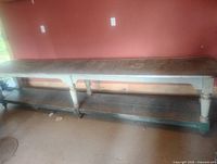 Full view of long antique table showing six legs, lower shelf, and steel-edged top