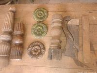 Baluster segments, floral rosettes, and bracket pieces laid on table