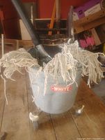 Front view of galvanized mop bucket on casters with White logo and mop inside