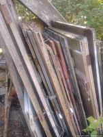 Stack of multiple solid wood doors leaning together outdoors