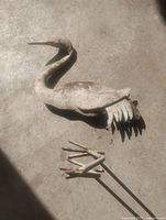 Top view of metal heron body and detached legs on concrete
