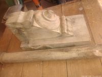 Wood block with carved volute and matching turned column section displayed on tabletop