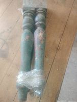 Two of the four wooden legs taped together showing full length, green paint wear