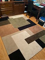 Full view of rug on floor showing geometric pattern and colors