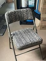 Front view of padded folding chair showing upholstery pattern and metal frame