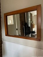 Front view of wood-framed wall mirror mounted on wall