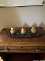 Overall view of three gold pears on dark leaf tray