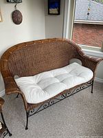 Full view of wicker and metal settee with cushion