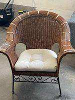 Front view of wicker chair showing shape, metal base, cushion