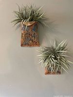 Both pottery wall pocket vases hanging on wall with faux foliage