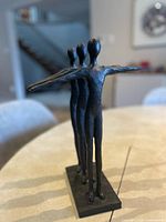 Full angled view of resin sculpture showing three figures and base