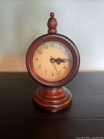 Full view of wooden clock on pedestal base