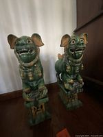 Front view of both green ceramic guardian lion statues on bases