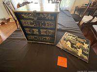 Front view showing drawers, top lid open, decorative panel beside