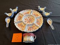 All items arranged: sectional snack plate, chicken dishes, spoons, teacup
