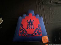 Front view of blue cushion showing red Asian motif and overall shape
