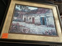 Full view of framed artwork showing cottage scene within mat and frame