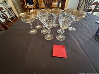 Group of 10 etched gold-rim stemware pieces on table