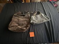 Two Michael Kors handbags side by side on surface