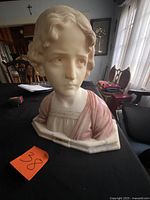 Front view of marble bust showing face, dress and title plaque