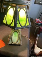 Lamp lit showing green stained glass panels and metal frame