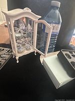 Cabinet open showing porcelain tea set inside next to water bottle for scale