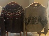Front view of both wool sweaters on chair backs showing patterns and condition