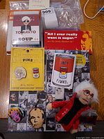 Full lot view showing puzzles, pins, finger puppet, chocolate bar, postcards, keychain