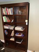 Full front view of tall dark wood bookcase with shelves