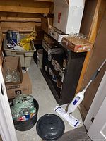 Overall view of shelving area showing tote and boxes of mason jars, canner pot, cleaning mop