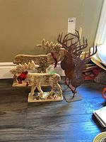 Group shot showing two birch bark moose figures with red bows and three rusted metal deer head silhouettes