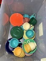 Top view of plastic bin filled with multicoloured Fiesta Ware cups, saucers and plates