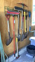 Wide shot of all long-handle tools hanging on wall rack