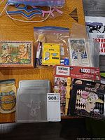 Overview of lot showing playing card tin, puzzle, stamp tins, mayonnaise sign, zip bag of pins, wooden block puzzle
