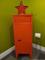 Front view of red metal cabinet showing drawer and cupboard