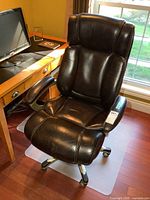 Front view of black leather high-back office chair positioned at desk